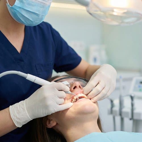 Hygienist performing a professional teeth cleaning with dental instruments
